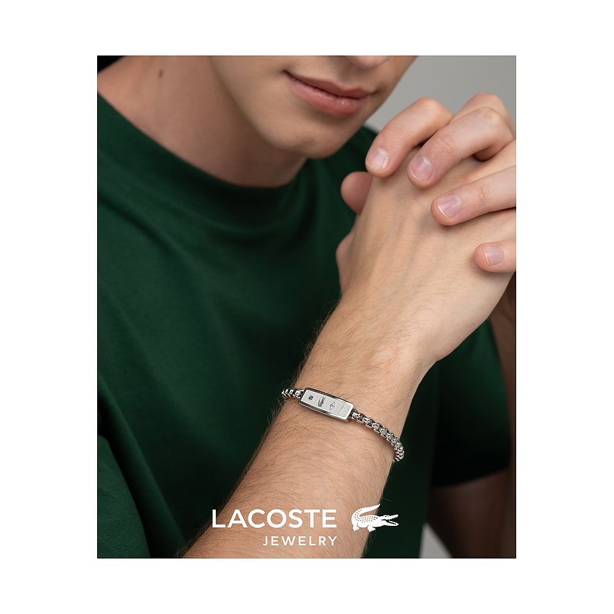 Close-up van man met zilverkleurige Lacoste roestvrijstalen schakelarmband met rechthoekig plaatje.