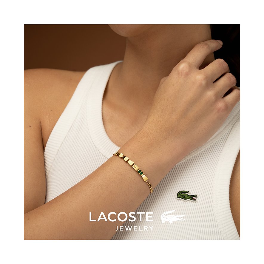 Lacoste armband gedragen om een pols, van goudkleurig roestvrij staal met groene kristallen kleurstenen.