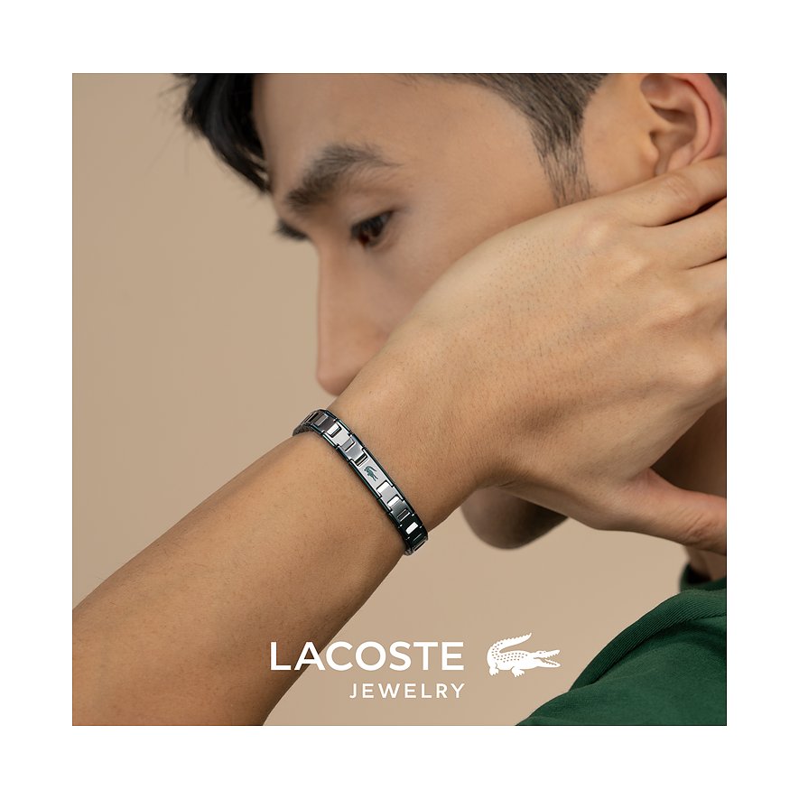 Close-up van een man met een roestvrijstalen Lacoste armband met krokodillenlogo om zijn pols.