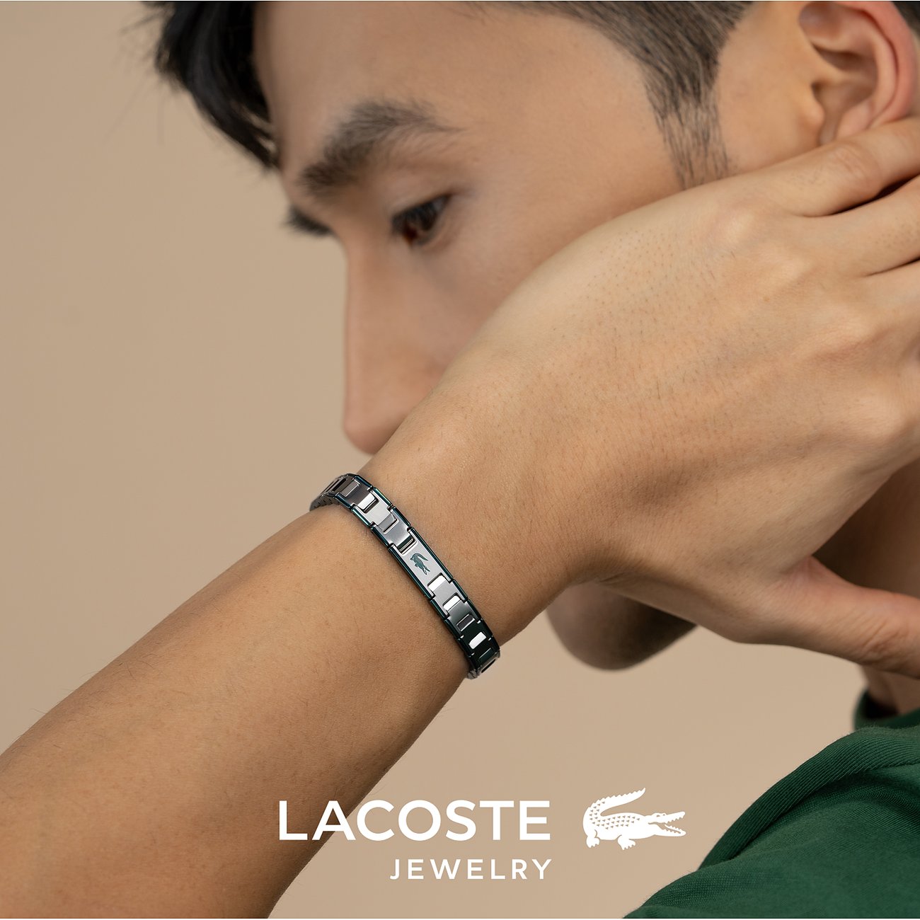 Close-up van een man met een roestvrijstalen Lacoste armband met krokodillenlogo om zijn pols.
