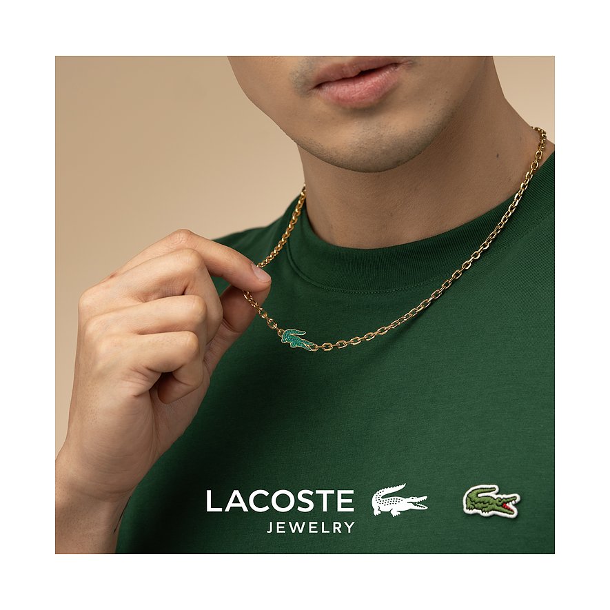 Nahaufnahme eines Mannes, der eine goldfarbene Lacoste Edelstahl-Halskette mit einem grünen Krokodil-Anhänger trägt.
