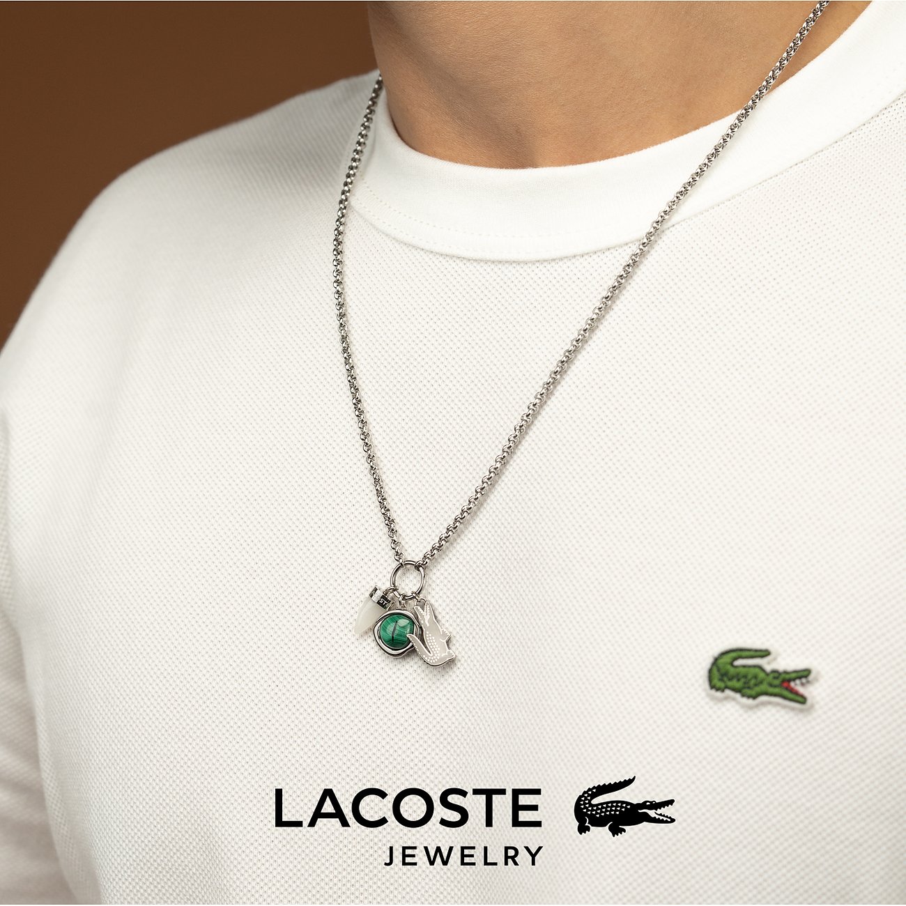 Nahaufnahme einer Person in weißem T-Shirt, die eine Lacoste Halskette aus Edelstahl mit Malachit-Anhänger trägt.