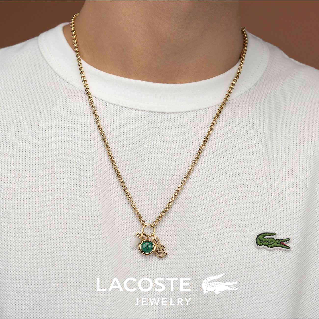 Lacoste Edelstahl-Halskette mit goldfarbenem Kesselmuster, grünem Malachit-Anhänger und Krokodil-Symbol.