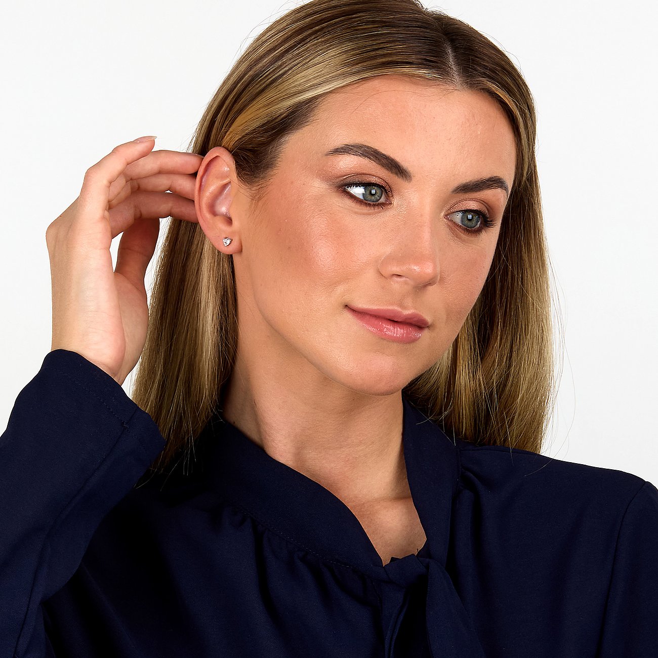Nahaufnahme eines Live Diamond Ohrsteckers aus weißem recyceltem 375er Gold mit Diamanten am Ohr einer Frau.