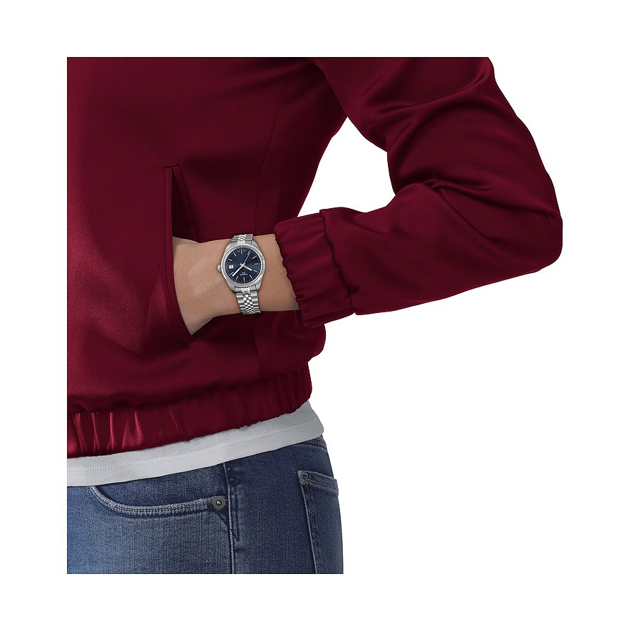 Tissot Damenuhr aus Edelstahl mit blauem Zifferblatt am Handgelenk einer Frau, deren Hand in einer Tasche steckt.